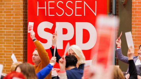 Delegierte halten beim SPD-Landesparteitag ihre Abstimmungskarten hoch. Im Hintergrund der Schriftzug: Hessen SPD