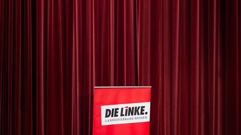 Aufsteller mit Parteilogo "Die Linke" vor rotem Vorhang 