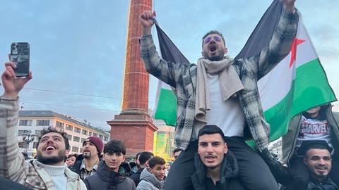 Mehrere Männer jubeln und halten die syrische Flagge in die Luft.