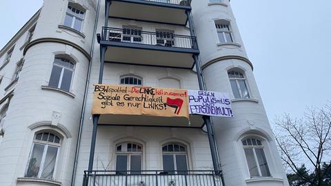 Ein Plakat hängt an einem Balkon eines Hauses. Darauf steht "BSW spaltet - Linke hält zusammen. Soziale Gerechtigkeit gibt es nur mit der Linken!"