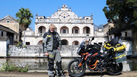 Tristan Duchscherer bei Guo Songnian Manor, China. Der blonde 22-Jährige steht in grauer Motorradkleidung neben seinem Motorrad. Er posiert vor Guo Songnian Manor in Wuhan, China.