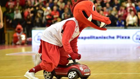 Das Maskottchen der Gießen 36ers, der Drache Fabius, fährt auf einem Bobbycar übers Parkett.