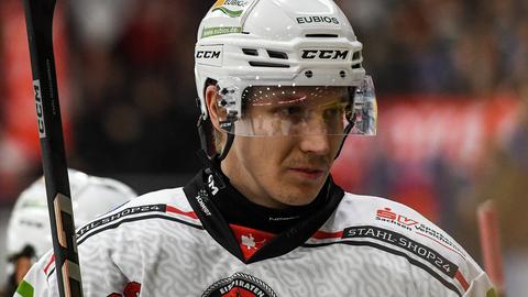 Henri Kanninen trägt Eishockeyhelm und schaut konzentriert nach rechts.