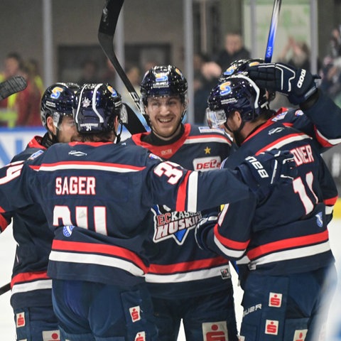 Die Spieler der Kassel Huskies jubeln zusammen. Tragen ein blaues Trikot.