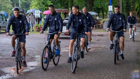 Die Mannschaft von Darmstadt 98 fährt mit dem Fahrrad im Regen zum Trainingsplatz.