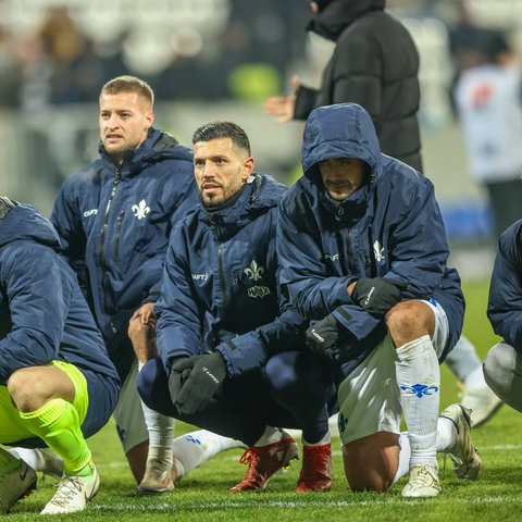 Die Lilien-Spieler hocken am Boden und warten auf ein "Humba" der Fans