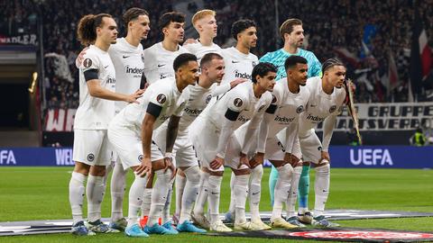 Eine Fußballmannschaft in weißen Trikots hat sich für ein Foto auf dem Fußballfeld gruppiert und alle posieren für die Kamera.