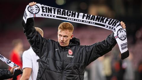 Hugo Larsson hält einen Eintracht-Schal in die Höhe.