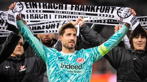 Kevin Trapp hält einen Schal der Eintracht in die Höhe.