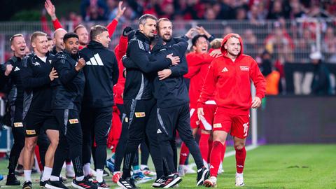 Betreuer und Auswechselspieler von Union Berlin jubeln an der Seitenlinie.