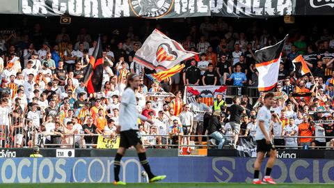 Spieler vom FC Valencia. Dahinter die Fans mit Fahnen.