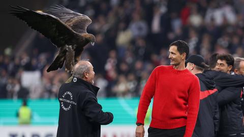 Eintracht-Trainer Dino Toppmöller weicht vor Maskottchen Attila zurück.