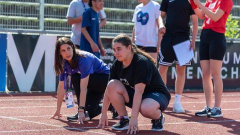 Teilnehmende bei einem inklusiven Sportfest in Fulda hocken am Start bei einer Laufdisziplin 