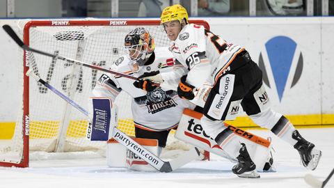 Zwei Eishockeyspieler rangeln vor dem Tor auf dem Spielfeld.