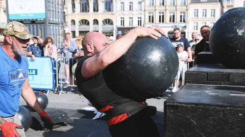 Strongman Volker Bauer hebt bei einem Kraftsport-Wettkampf ein kugelförmiges Gewicht in die Höhe 