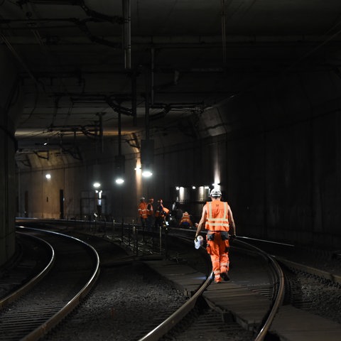 Ein dunkler Tunnel, Männer in orangenen Arbeitsanzügen