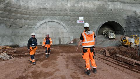 Bauarbeiter mit Helmen vor Tunnel-Baustelle