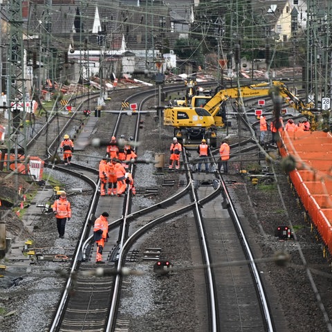 Auf Bahngleisen sind Bauarbeiter unterwegs.