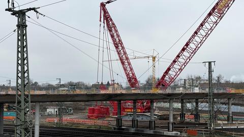 Ein großer roter Kran steht an der Baustelle an der Brücke am Hauptbahnhof