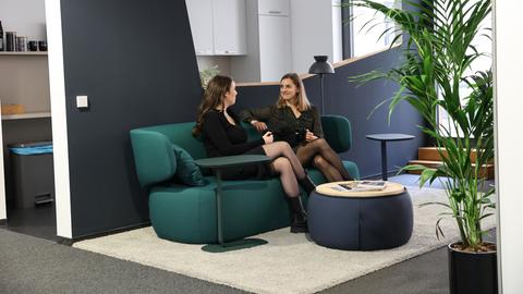 Zwei Frauen sitzen auf einer grünen Couch.