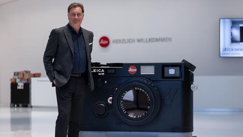 Der Vorstandsvorsitzender der Leica Camera AG, Matthias Harsch, steht vor einem großen Modell einer Leica-Kamera.