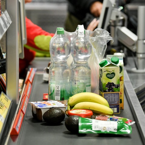 Lebensmittel liegen auf dem Band an einer Kasse in einem Supermarkt.