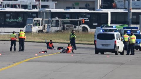 Einsatzkräfte stehen am Frankfurter Flughafen, wo sich zwei Aktivisten festgeklebt haben. 