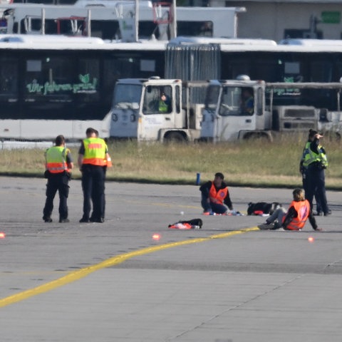 Einsatzkräfte stehen am Frankfurter Flughafen, wo sich zwei Aktivisten festgeklebt haben. 