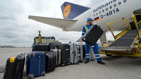 Ein Vorfeld-Mitarbeiter lädt auf dem Flughafen in Frankfurt Koffer in eine Lufthansa-Maschine.