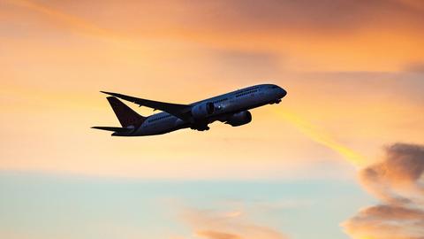 Ein Flugzeug während des Fluges umgeben von orang-rotem Himmel.