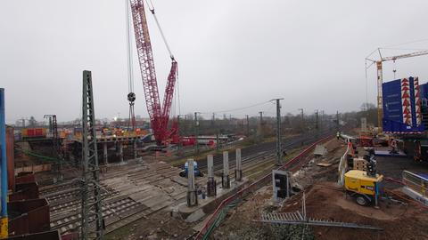 Ein Kran trägt Teile der abgerissenen Brücke am Hanauer Hauptbahnhof.