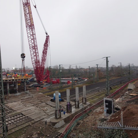 Ein Kran trägt Teile der abgerissenen Brücke am Hanauer Hauptbahnhof.