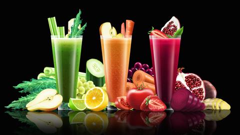 Grüner, orangefarbener und roter Obst-Gemüsesaft in drei Gläsern. Drum herum viel Frischobst und Gemüse.