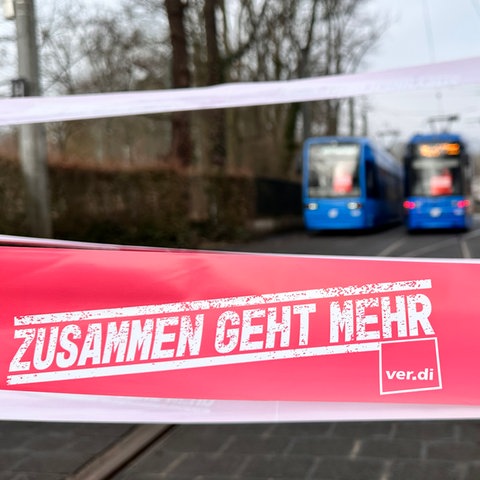 Verdi-Schriftzug "Zusammen geht mehr", im Hintergrund stehende Straßenbahnen