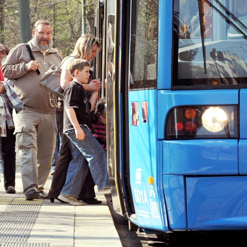 Menschen steigen in einen Bus an einer Haltestelle in Kassel.