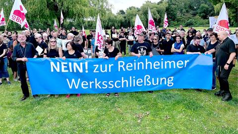 Eine Menschenmenge hält ein blaues Banner auf welchem in weißer Schrift "NEIN! zur Rheinheimer Werksschließung" steht