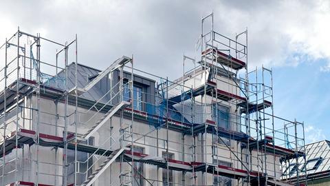 Foto von einem Mehrfamilienhaus mit Gerüsten vor der Fassade.