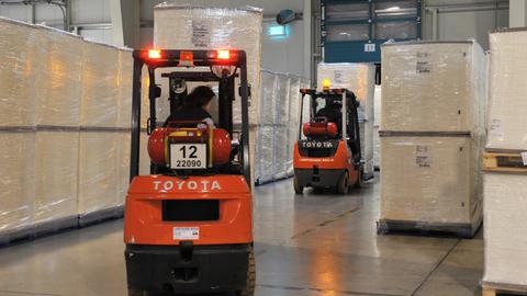 Gabelstapler fahren durch Fabrikhalle mit verpackten Papierstapeln