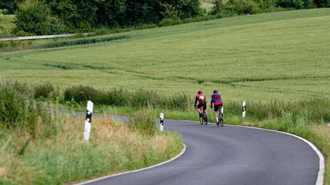 Zwei Radfahrer fahren auf einer Landstraße - ein Radweg fehlt.