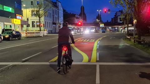 Radfahrer steht bei Dunkelheit an einer roten Ampel.