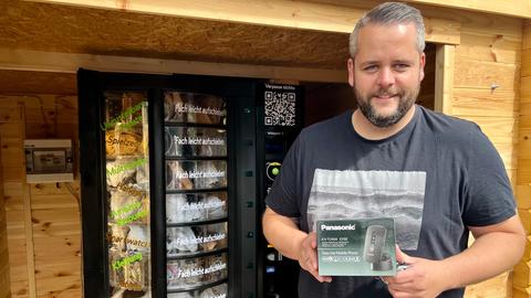 Mann hält Paket mit Klapphandy hoch