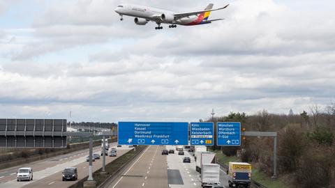 Autos auf einer mehrspurigen Autobahn, ein Flugzeug im Landanflug auf den nahem Flughafen