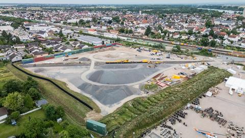 Ein Bauzug und Baufahrzeuge stehen auf der Baustelleneinrichtungsfläche bereit (Luftaufnahme mit einer Drohne)