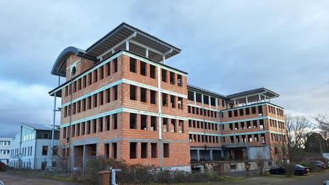 Leerstehender Hotel-Rohbau in Groß-Gerau: "Zwischen anderen Häusern stehen die Backsteinwände des leerstehenden Hotel-Rohbaus auf einer mit einem Zaun abgesperrten Fläche.