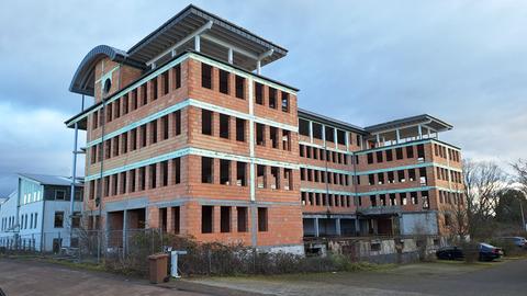 Leerstehender Hotel-Rohbau in Groß-Gerau: "Zwischen anderen Häusern stehen die Backsteinwände des leerstehenden Hotel-Rohbaus auf einer mit einem Zaun abgesperrten Fläche.