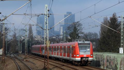 Eine rote S-Bahn fährt auf einem Gleis vor der Frankfurter Skyline