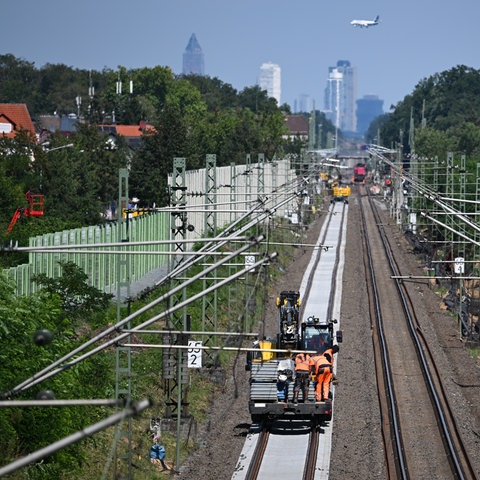 Arbeiter sind mit einem Spezialgerät auf einem sanierten Gleis zwischen Mörfelden-Walldorf und Walldorf (im Hintergrund) im Einsatz.