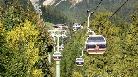 Eine Seilbahn mit Kabinen führt über bewaldete Hügel