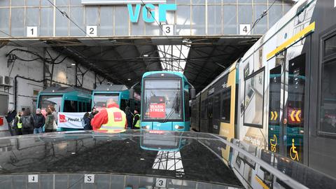 Straßenbahnen stehen im Depot der VGF, daneben stehen Bahnfahrer in Warnwesten. 