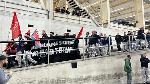 Mitgleider der Jugend der IG Metall kommt eine Rampe in die Halle runter. Sie tragen ein schwarzes Banner mit der Aufschrift "Übernahme sichern - for our future"